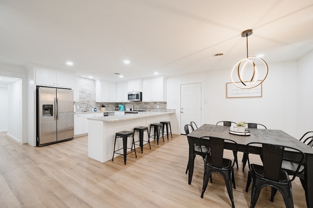 dining area with light hardwood / wood-style flooring, a notable chandelier, and sink