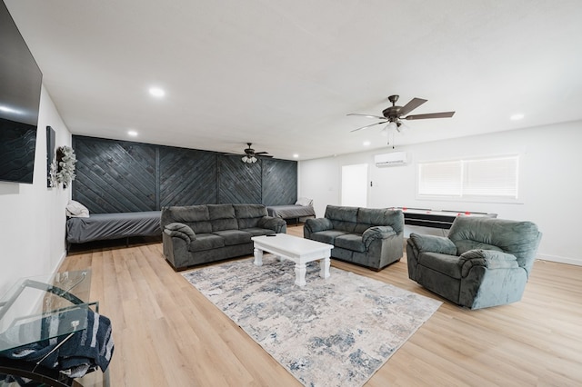 living room featuring light hardwood / wood-style floors, an AC wall unit, and ceiling fan