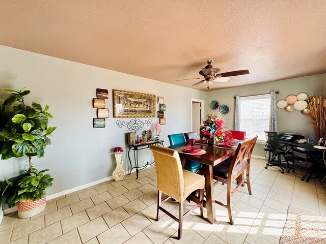 dining area featuring light tile patterned floors, a ceiling fan, baseboards, and a textured ceiling