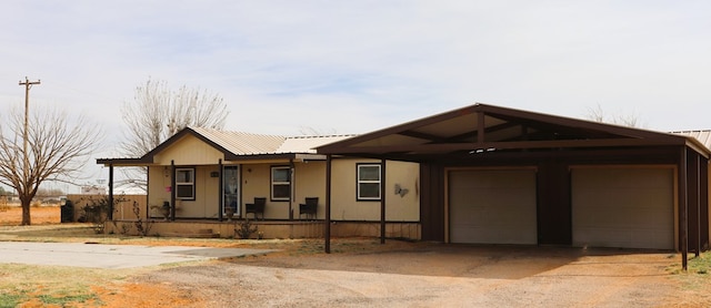 ranch-style house with a carport, a porch, metal roof, and a garage