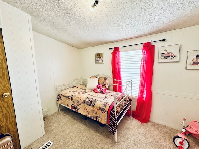 carpeted bedroom with visible vents and a textured ceiling