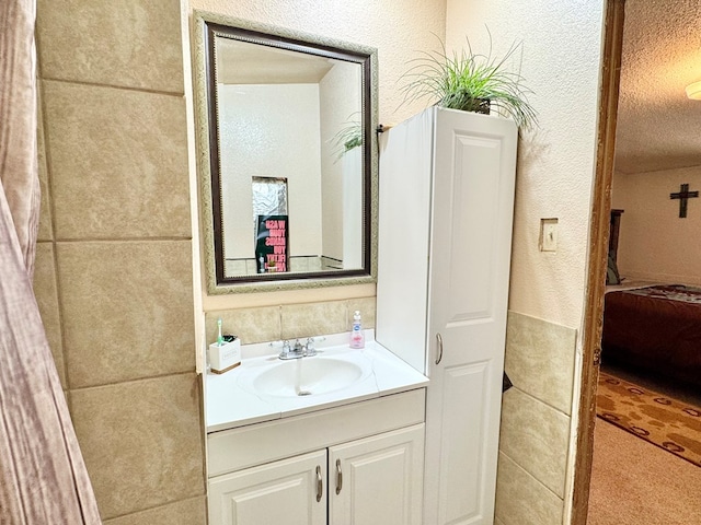 bathroom with tile walls, vanity, and a textured wall