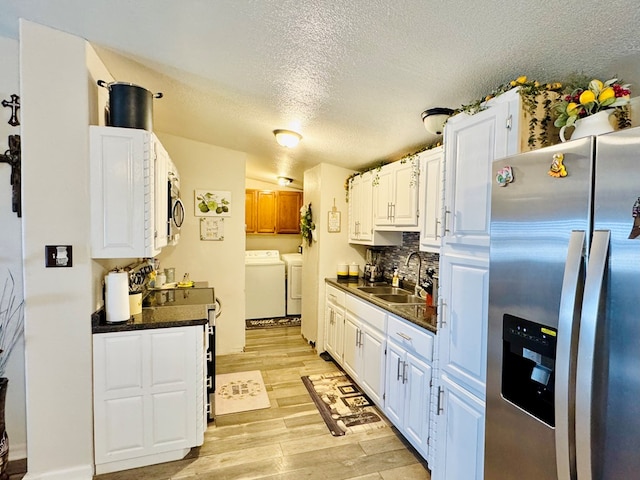 kitchen with dark countertops, independent washer and dryer, stainless steel appliances, and a sink