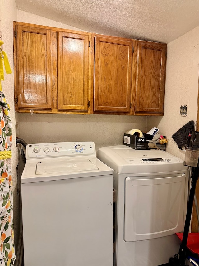 washroom featuring cabinet space, separate washer and dryer, and a textured ceiling