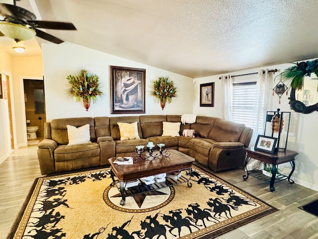 living room with light wood-style flooring, a textured ceiling, lofted ceiling, and ceiling fan