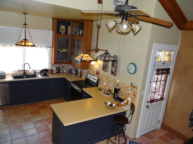 kitchen featuring kitchen peninsula, appliances with stainless steel finishes, tasteful backsplash, sink, and decorative light fixtures