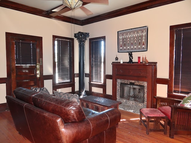 living room featuring hardwood / wood-style floors, ceiling fan, a fireplace, and crown molding