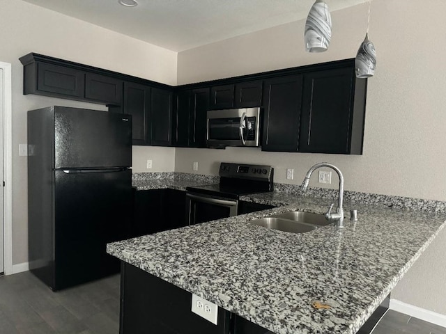 kitchen with kitchen peninsula, light stone countertops, sink, and appliances with stainless steel finishes