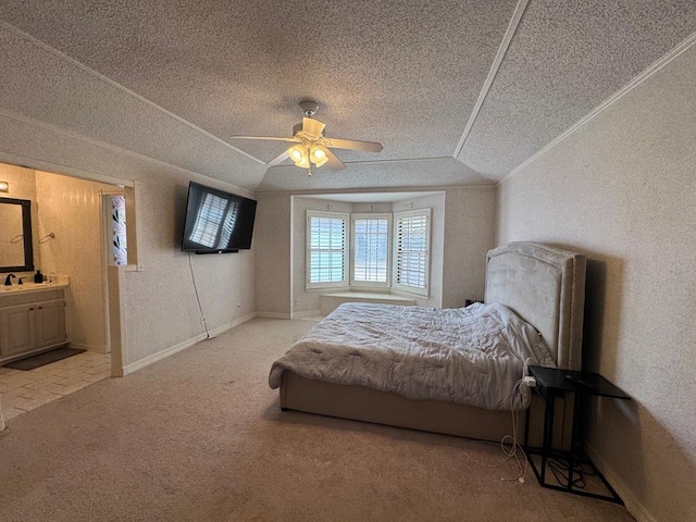 carpeted bedroom with vaulted ceiling, connected bathroom, ceiling fan, crown molding, and a textured ceiling