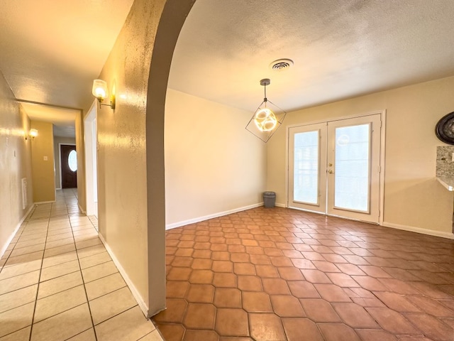 interior space with french doors, a textured ceiling, and tile patterned floors