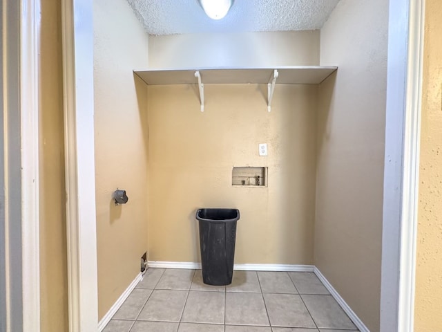 clothes washing area with hookup for a washing machine, light tile patterned floors, and a textured ceiling