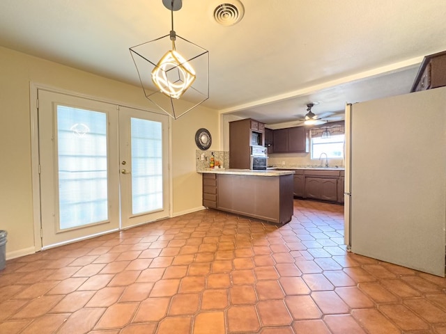 kitchen with kitchen peninsula, french doors, ceiling fan, sink, and white fridge