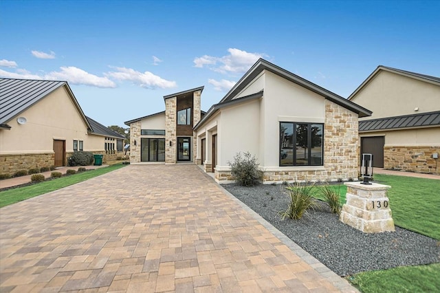 exterior space with stone siding, stucco siding, decorative driveway, and a garage