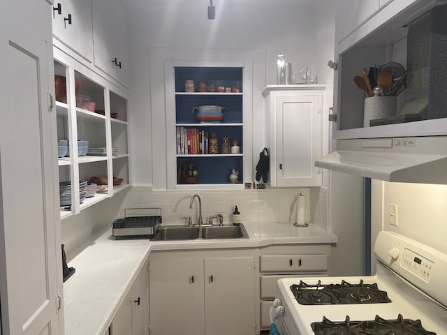 kitchen with white gas range, sink, tile counters, decorative backsplash, and white cabinets