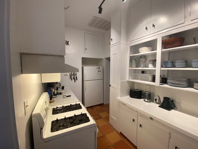 kitchen featuring dark tile patterned flooring, white appliances, and white cabinetry