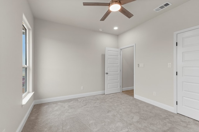 unfurnished room with light colored carpet and ceiling fan