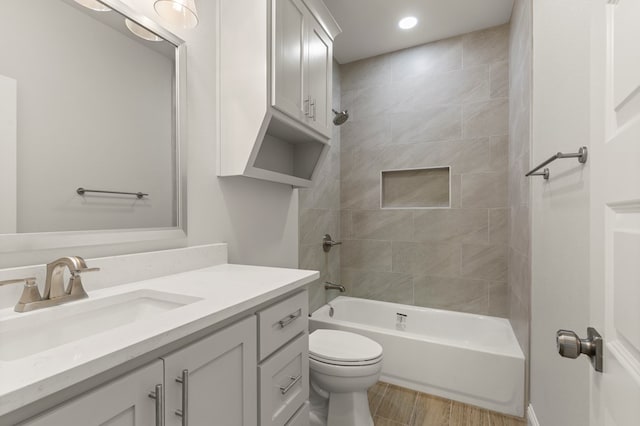 full bathroom featuring hardwood / wood-style flooring, tiled shower / bath, vanity, and toilet