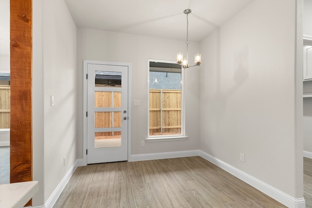 unfurnished dining area with an inviting chandelier and light hardwood / wood-style floors