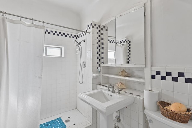 bathroom featuring tiled shower, a sink, tile walls, and toilet