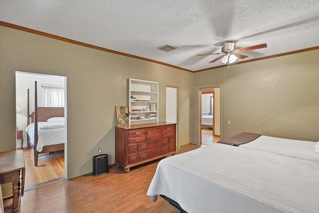 bedroom featuring visible vents, a ceiling fan, light wood-style flooring, a textured ceiling, and crown molding