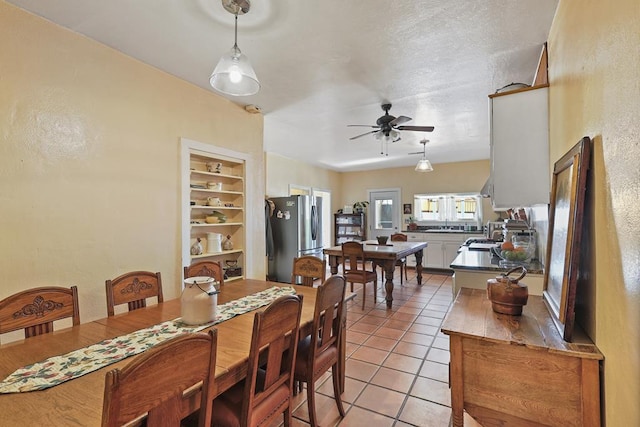 dining area featuring built in shelves, ceiling fan, a textured ceiling, and light tile patterned floors