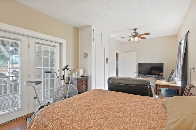 bedroom featuring ceiling fan, access to outside, a textured ceiling, and wood finished floors