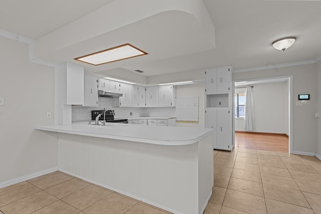 kitchen with white cabinetry, kitchen peninsula, decorative backsplash, and light tile patterned floors