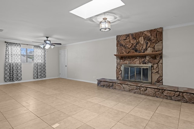 unfurnished living room with ceiling fan, a skylight, a fireplace, ornamental molding, and light tile patterned flooring