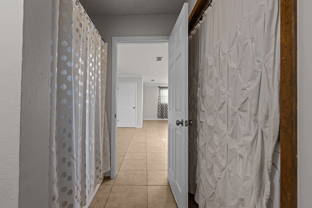 corridor with light tile patterned flooring and a textured ceiling