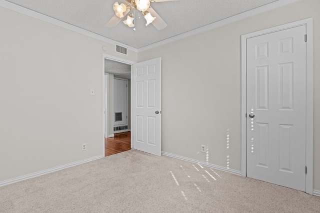 unfurnished bedroom featuring ceiling fan, ornamental molding, a textured ceiling, and carpet