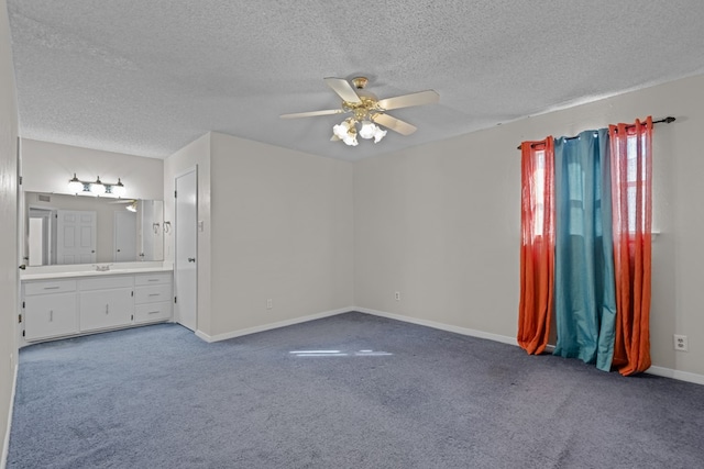 carpeted spare room featuring ceiling fan, sink, and a textured ceiling