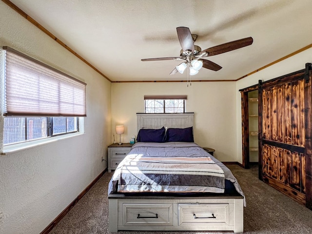 carpeted bedroom with crown molding, a barn door, a ceiling fan, and baseboards