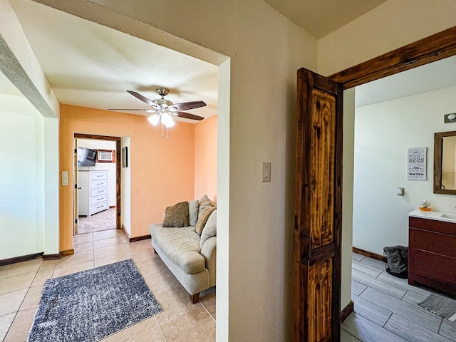 living room with light tile patterned floors, baseboards, and ceiling fan