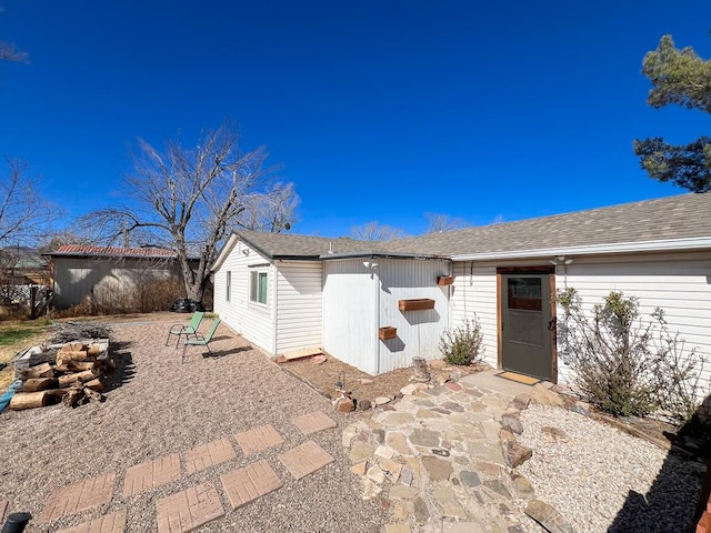 back of property with a patio area and a shingled roof