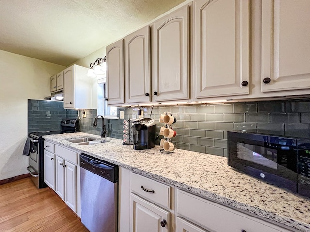 kitchen with light wood finished floors, light stone countertops, under cabinet range hood, appliances with stainless steel finishes, and a sink