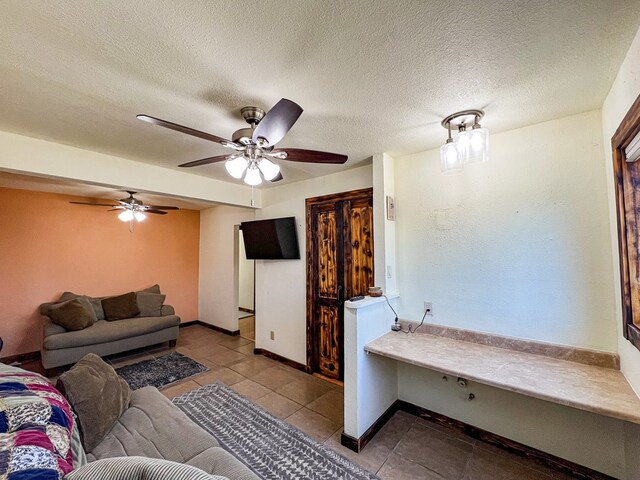 tiled living room featuring baseboards, a textured ceiling, and a ceiling fan