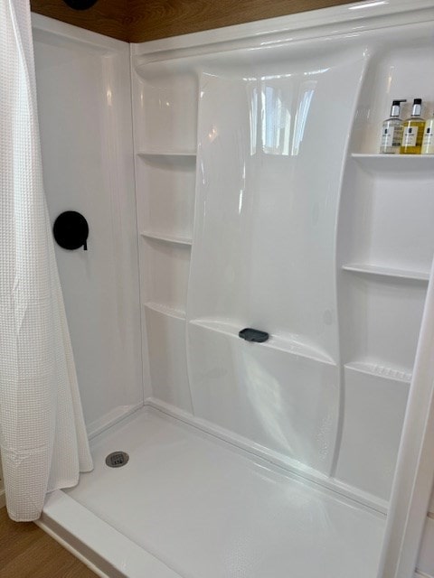 bathroom with a shower stall and wood finished floors