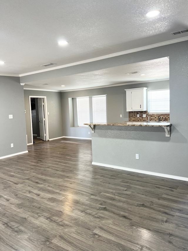 unfurnished living room featuring dark hardwood / wood-style flooring, a textured ceiling, and ornamental molding