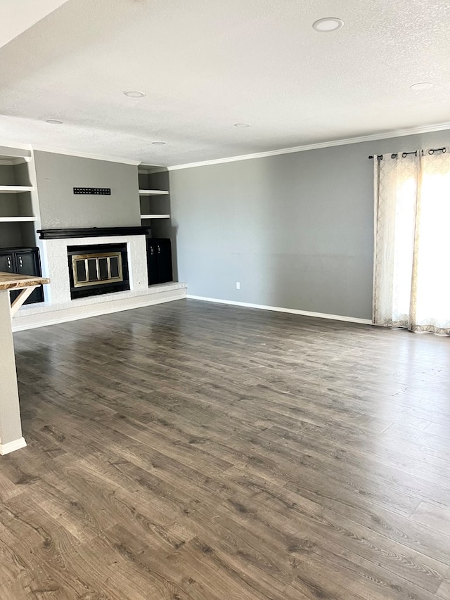 unfurnished living room featuring built in shelves, a textured ceiling, dark hardwood / wood-style floors, and ornamental molding