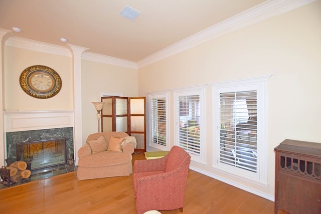 living room featuring ornate columns, crown molding, a premium fireplace, and hardwood / wood-style flooring