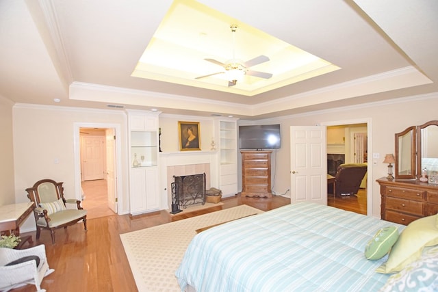 bedroom with light hardwood / wood-style flooring, a raised ceiling, ceiling fan, and crown molding