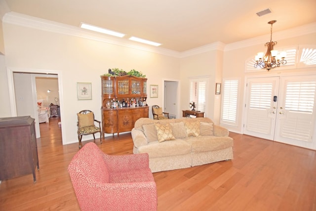 living room featuring hardwood / wood-style floors, ornamental molding, plenty of natural light, and a notable chandelier