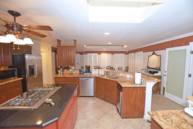 kitchen featuring a center island, sink, ceiling fan, light stone counters, and stainless steel appliances