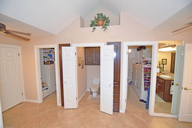 tiled bedroom featuring ceiling fan, sink, washer / clothes dryer, ensuite bathroom, and vaulted ceiling