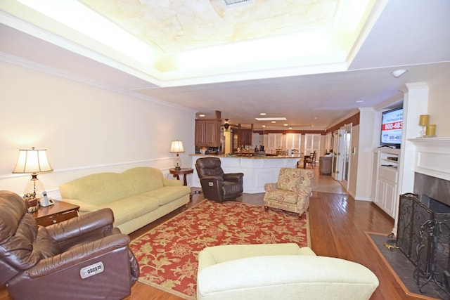 living room featuring hardwood / wood-style floors, a raised ceiling, and crown molding