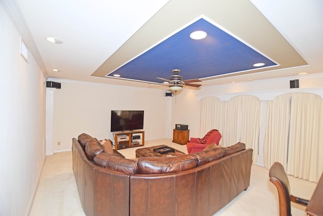 living room with a raised ceiling, crown molding, ceiling fan, and light carpet