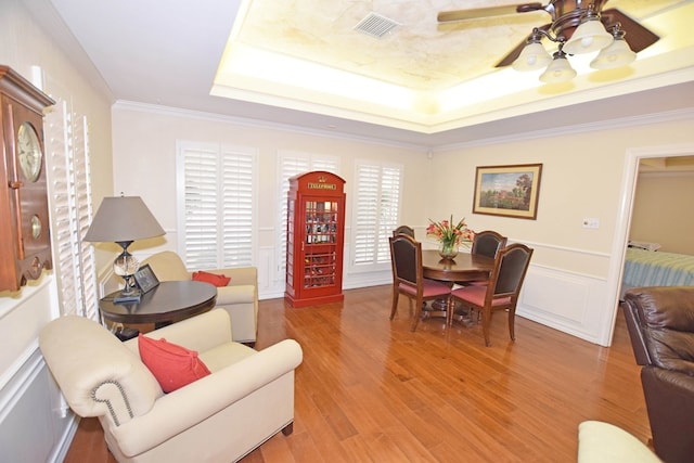 interior space featuring ceiling fan, a raised ceiling, ornamental molding, and light hardwood / wood-style flooring