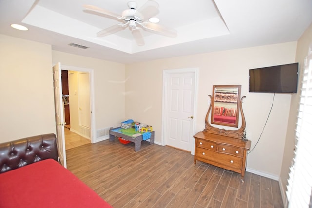 bedroom featuring dark hardwood / wood-style flooring, a raised ceiling, and ceiling fan