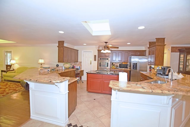 kitchen featuring sink, a skylight, ornamental molding, appliances with stainless steel finishes, and kitchen peninsula