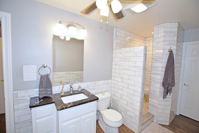 bathroom with vanity, ceiling fan, tile walls, tiled shower, and wood-type flooring